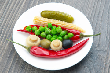 salad of canned and pickled olives, mushrooms, corn, peas, cucumber and red pepper on a white plate.  food and vegetables. diet and weight loss