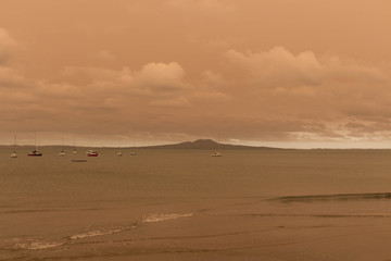 A haze from Australia's bushfires hangs over Torbay Beach, North Shore district of Auckland, New Zealand.