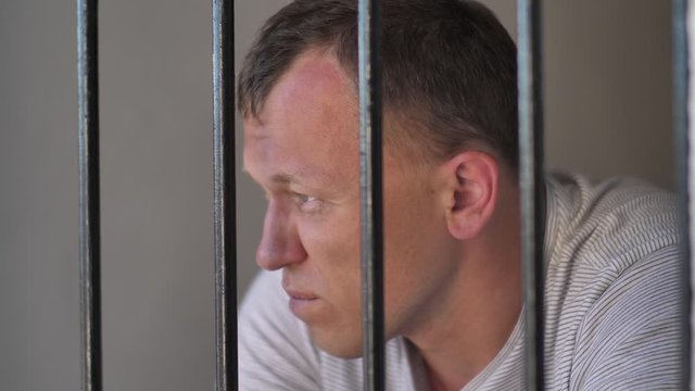 man behind bars in prison is thinking about something, a bad emotion