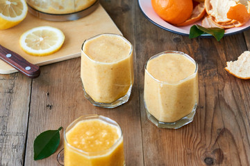 Glasses of citrus smoothies on a wooden background