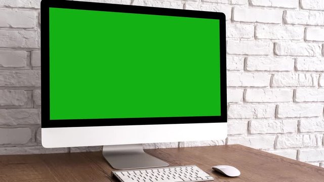 Mock up green screen computer desktop with keyboard and mouse on wooden table. Work place concept with chroma key.