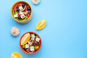 Fototapeta na wymiar Bowls of tasty Greek salad on color background