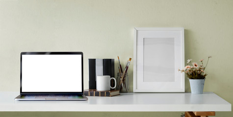 Cropped shot of open blank screen laptop computer with office supplies and mock up frame