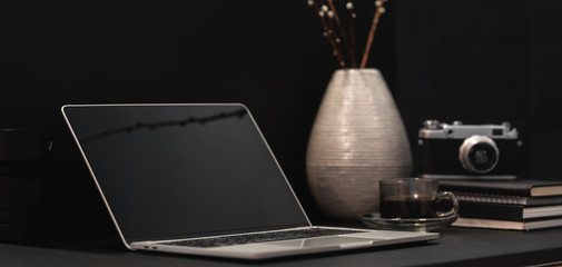 Cropped shot of dark modern designer workplace with open laptop computer