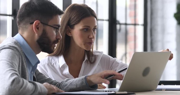 Male professional mentor help teach female worker explain computer software