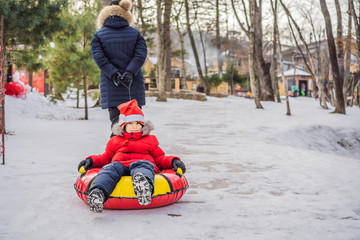 mom son ride on an inflatable winter sled tubing. Winter fun for the whole family