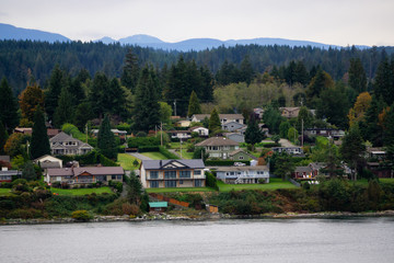Fototapeta na wymiar Campbell River, Vancouver Island, British Columbia, Canada. Beautiful view of residential homes on the ocean shore during a cloudy evening.