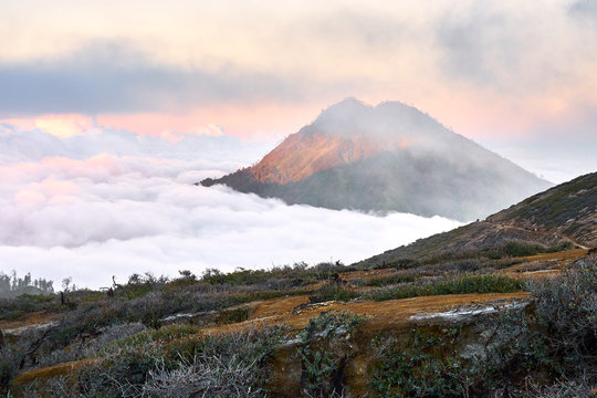 Volcano peak rising above the clouds at sunrise, Ijen mountain, East Java, Indonesia