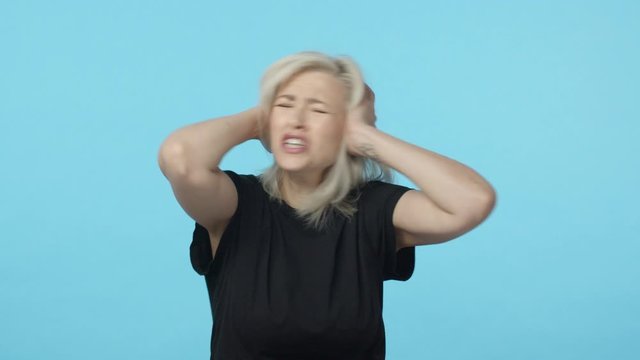 Woman in denial unwilling hear painful truth. Slow-motion upset and distressed, mad blond female have argument, shut ears and haking head in refusal, asking stop, dont want listen, blue background
