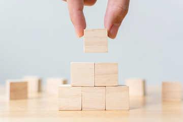 Hand arranging wood block stacking as step stair on top pyramid. Business concept for growth...
