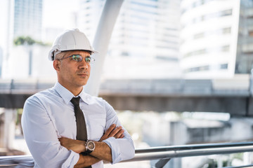 Business man, civil engineer wear a white safety helmet smiling and working with arms crossed in...