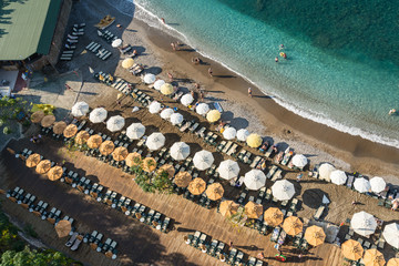 Turkish beach filled with holidaymakers, rows of sun loungers and parasols