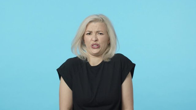 Girl cringe from disgust. Slow-motion displeased and bothered, blond woman grimacing with aversion, frowning wanting puke from just imaging something awful, standing blue background