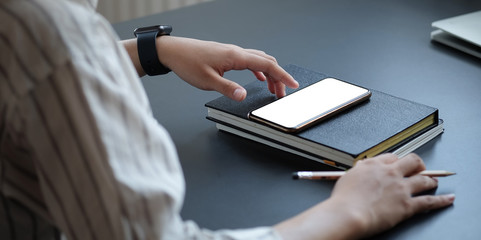 Cropped shot view of woman hands holding smart phone with blank copy space screen for your text message or information content, female reading text message on cell telephone during in urban setting. 