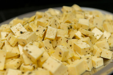 Close up of diced cheese to be served at party. Cheese seasoned with oregano, salt and olive oil. Delightful to be enjoyed and accompanied by beer. Selective focus.
