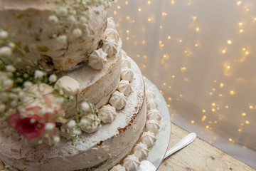 Top view. Beautiful white tree tier cake with fresh flowers with fairly light and lanterns glowing in the background.
