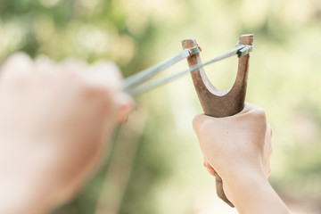 Human pulling slingshot and ready to fire.