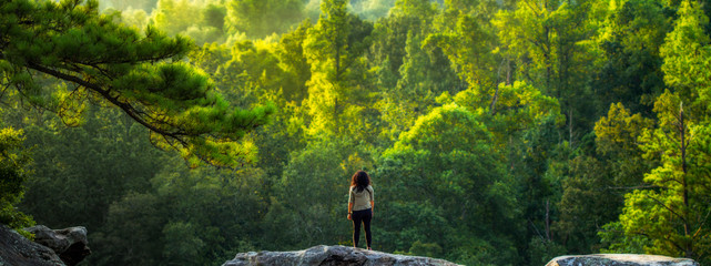 A young female hiker takes a break to enjoy a forest view. - Powered by Adobe