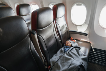 Child of two years old is sleeping on board an airplane. Comfortable flights with the baby.