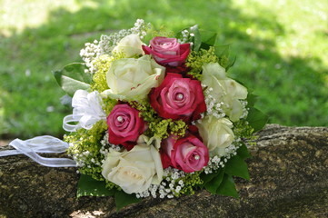 Wunderschöner Brautstrauß weiße und rosa Rosen auf Baumstamm in Sonne
