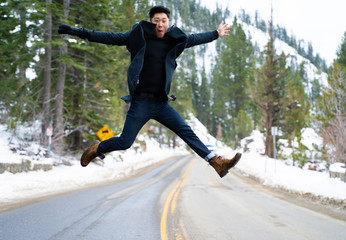 Young asian hipster male jumping in road in winter