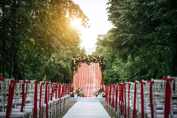 Arch decorated with fresh flowers and fabric for wedding ceremony outdoor. Solemn wedding registration in the park.