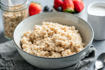 Oatmeal porridge, cooked steel cut oats in bowl. Healthy breakfast food
