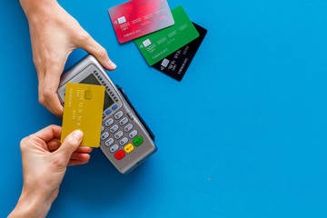 Contactless payment, paypass. Hand hold bank card near terminal on blue background top-down copy...
