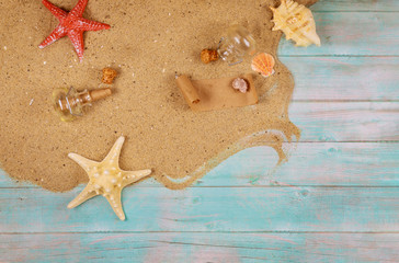 Vacation concept background with sand, shells and starfish. Papyrus from the glass bottle with cork.