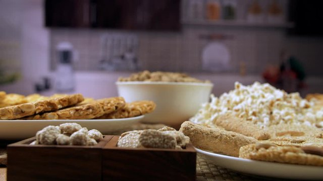 Zoom out shot of edible items consumed during the festival of Lohri and wintertime. Moving shot of beautifully plated groundnuts  peanuts chikki  popcorns  rewri  gajak rolls  and til patti with a ...