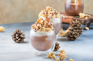 Cold chocolate dessert with whipped cream, popcorn and caramel topping in glasses on beige background, place for text