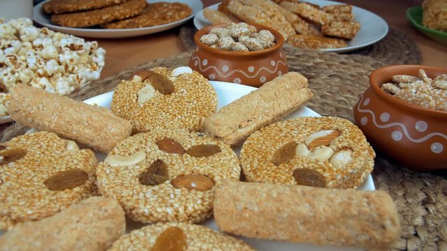 Closeup shot of til patti  gajak rolls  and rewri rotating on a turntable - Lohri festival. Pan shot of various Lohri items like gajak rolls  til patti  rewri  bhujia chikki  popcorns  murmura chik...