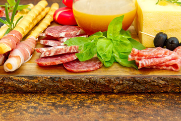 Meat and cheese plate antipasti snack with Prosciutto ham, Parmesan, Blue cheese, Cantaloupe melon and Olives on olive wood serving board on dark stone background