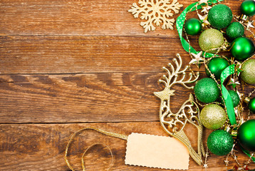 Christmas greeting card. Green balls, deer, golden snowflake and label on a wooden background. Top view. Text space.