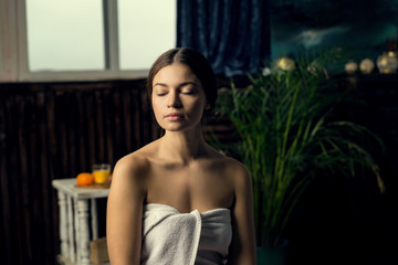Obraz na płótnie Canvas Young beautiful girl in a towel with closed eyes meditates before spa treatments.