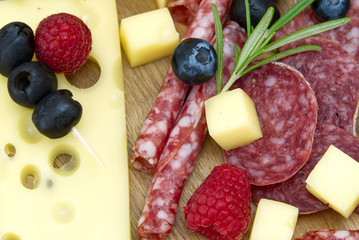 Meat and cheese plate antipasti snack with Prosciutto ham, Parmesan, Blue cheese, Cantaloupe melon and Olives on olive wood serving board on dark stone background