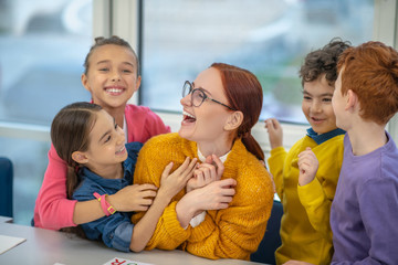 Happy and joyful pupils hugging their favourite teacher