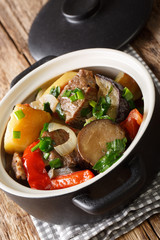 Traditional Georgian meat chanakhi with vegetables in a pot close-up on the table. vertical