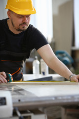 Arms of worker measuring wooden bar closeup