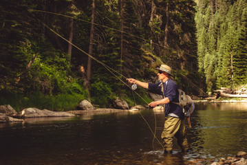 A fly fisherman fishing for trout on the mountain river in Northern Idaho. - Powered by Adobe