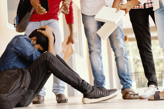 Teenage Boy Being Bullied At School, covered his face - group of students threatening to hit classmate or junior at university - Concept of teasing, bulling or warning at college campus.