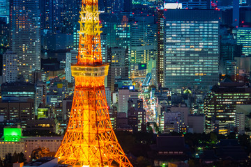 Japan. Tokyo. Minato. A fragment of the TV tower of Tokyo in close-up. Orange tower on the background of the evening city. Tokyo office buildings next to the TV tower. Top view of the evening capital.