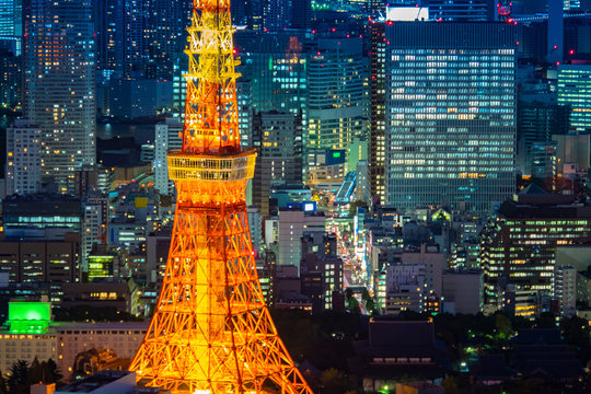 Japan. Tokyo. Minato. A fragment of the TV tower of Tokyo in close-up. Orange tower on the background of the evening city. Tokyo office buildings next to the TV tower. Top view of the evening capital.