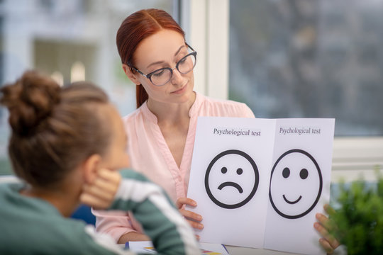 Concentrated teacher showing her pupil psychological tests