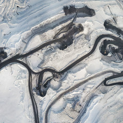 Winter quarry top view. Aerial view the winter quarry. Roads with mining equipment in winter view from above