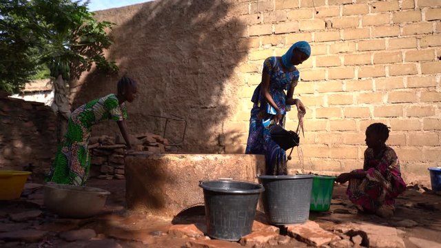 Group of African Girls Filling Up Water Buckets At the Village Well