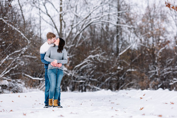 Fototapeta na wymiar Love Valentine Concept. people, season, love and leisure concept - happy couple hugging and kissing outdoors in winter. Romantic couple in love feeling happiness romance Valentine . love copy space.