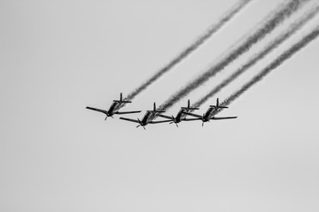 four airplane demonstrate in an event black and white