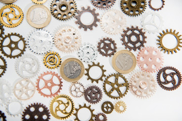 Clock gear wheels on white table with euro coins. Money currency abstract photo.