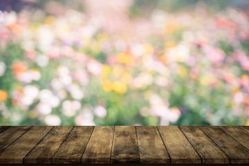Empty wood table top on blurred flowers garden background.